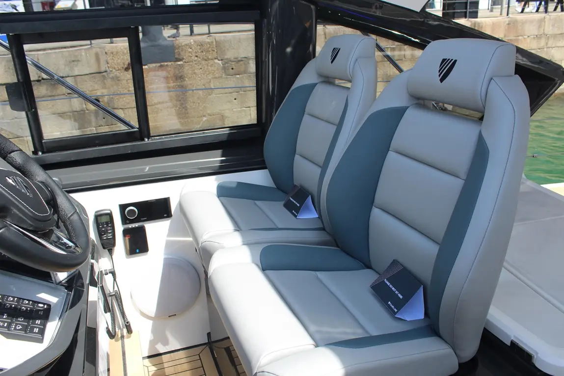Stylish grey and blue boat seats face forward, with a sleek steering wheel and controls visible in the cockpit.
